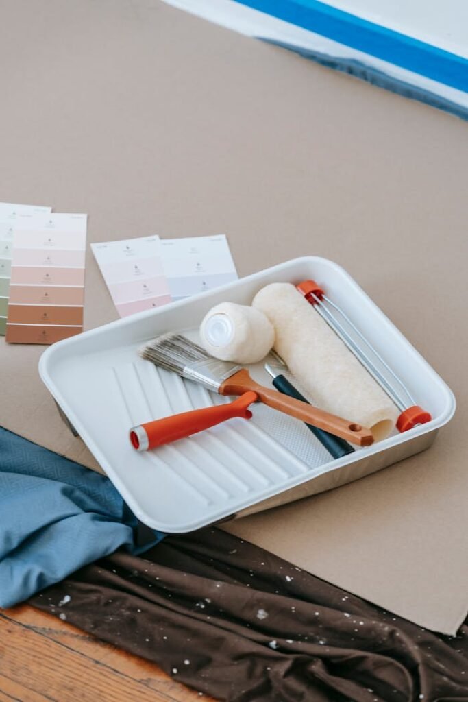 pexels-photo-7217952 Paintbrush, roller, tray, and swatches for home renovation projects.